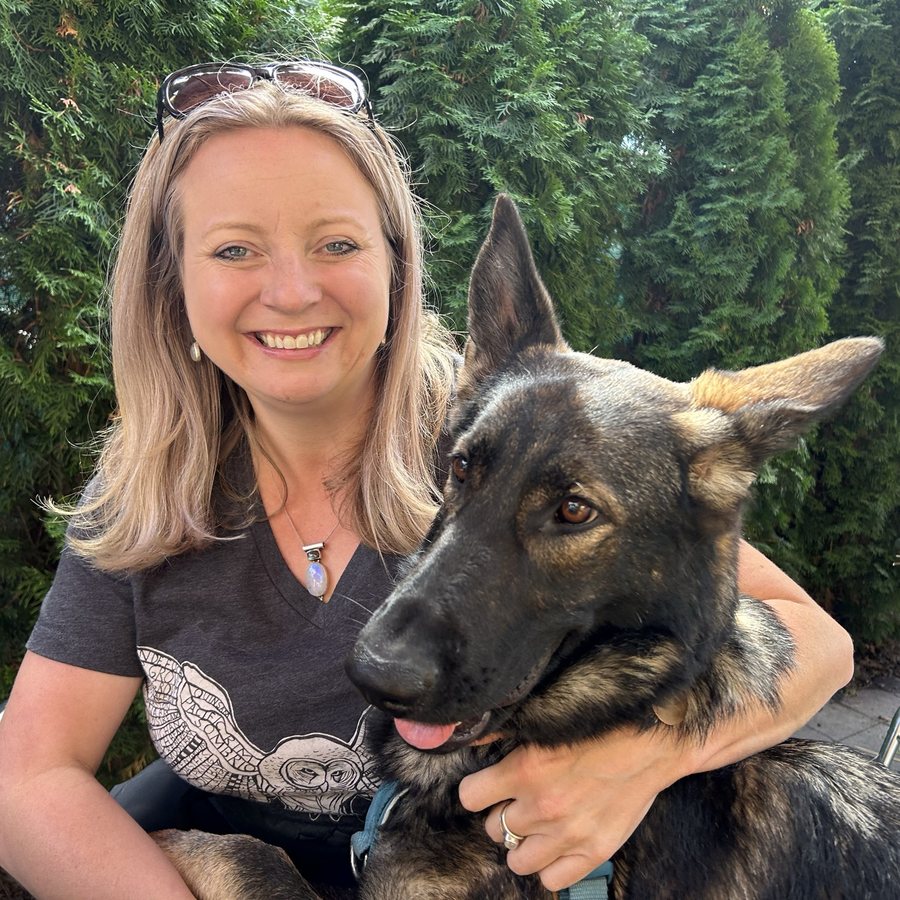 A smiling woman hugging a German shepherd